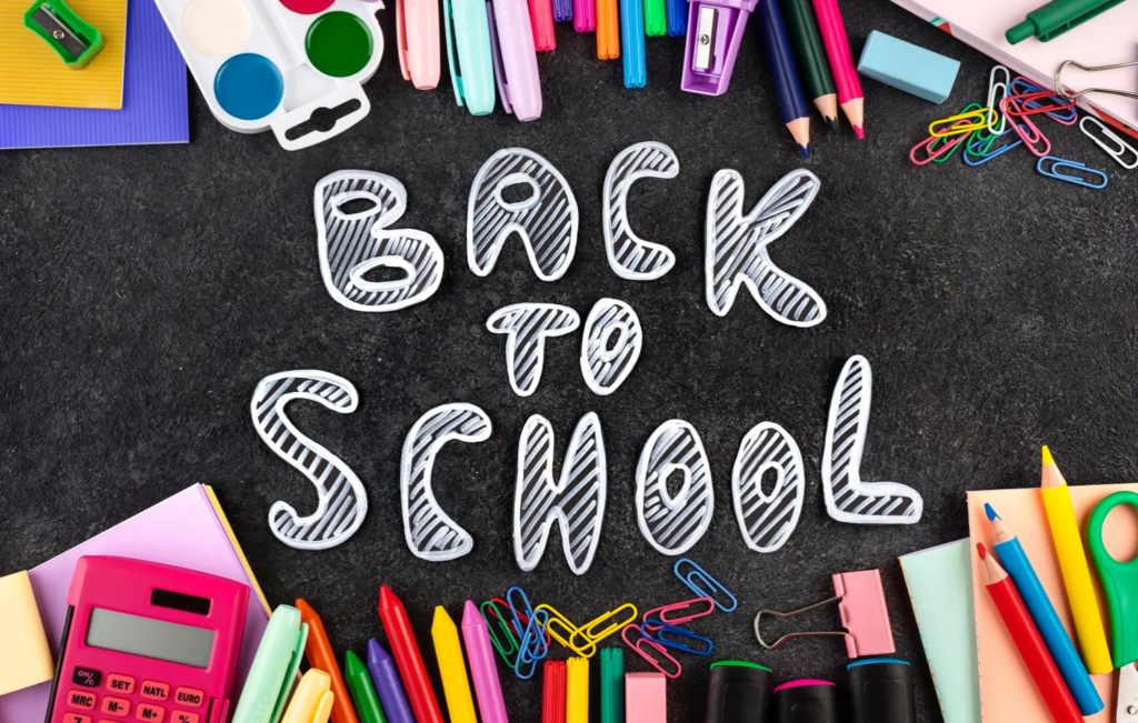 A top-down view of vibrant school supplies framing the words "Back to School" written on a chalkboard background.