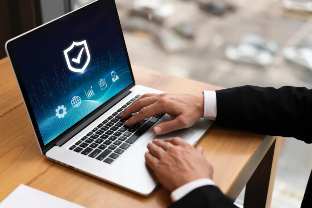 A business professional typing on a laptop displaying a cybersecurity shield and data security dashboard.